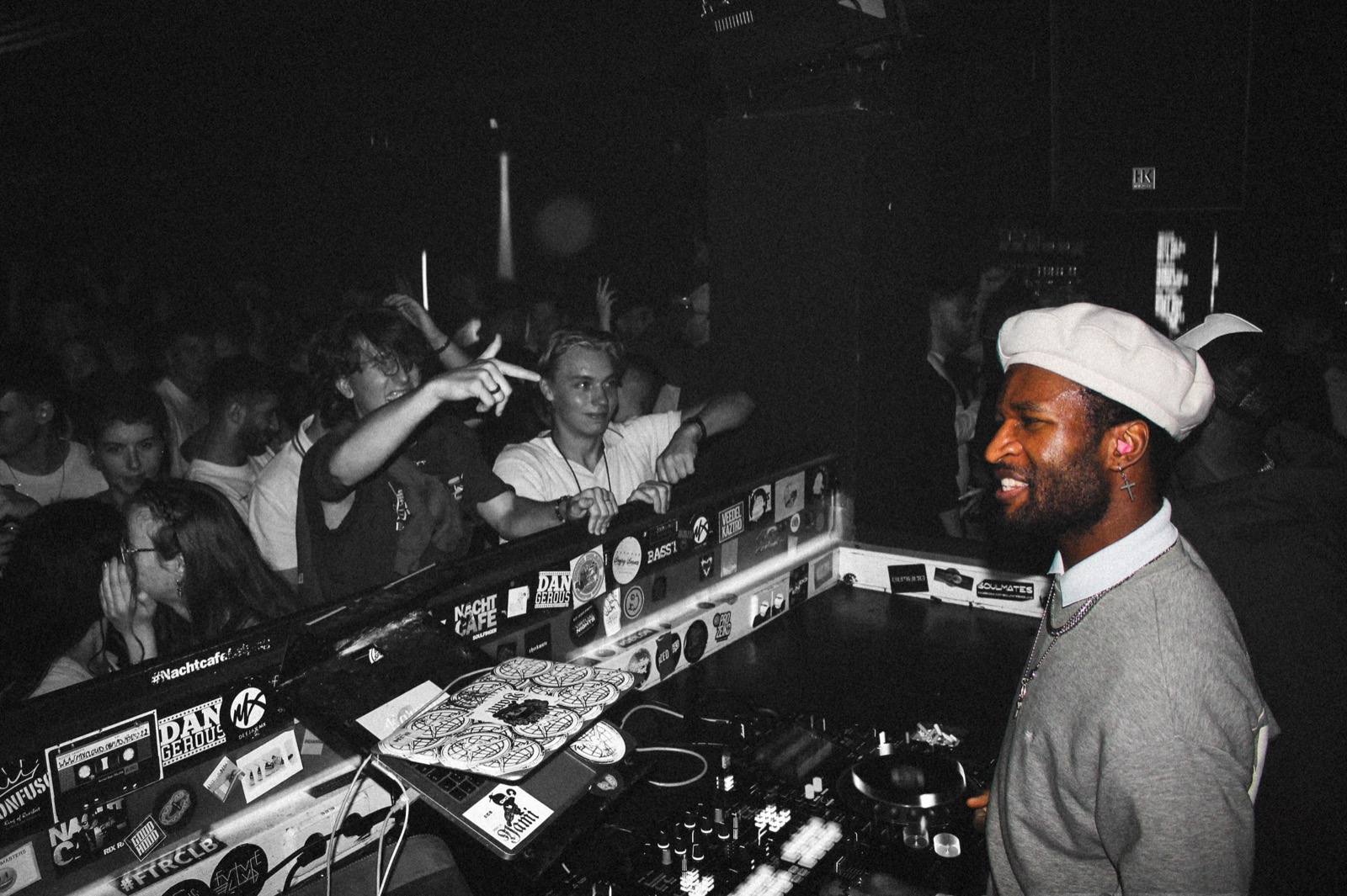 DJ am Mischpult vor begeisterter Menge im Club