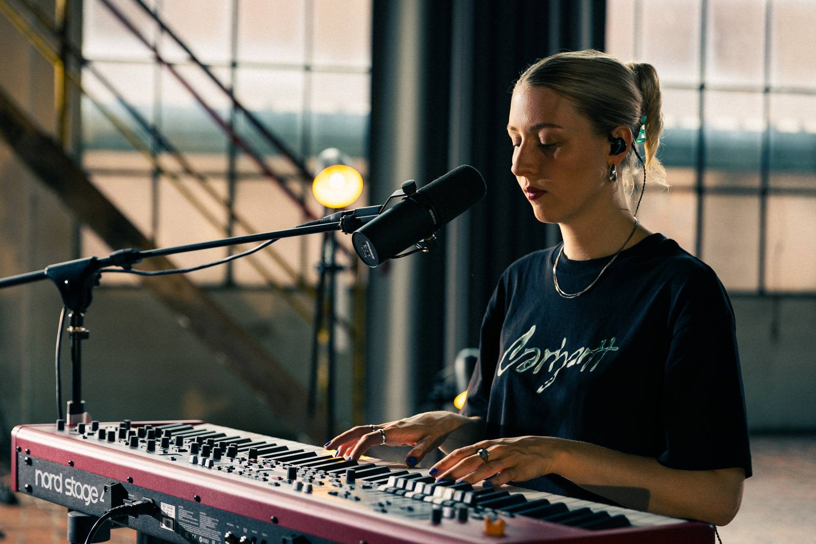 Musikerin spielt Nord-Stage-Keyboard, im Hintergrund Industriefenster